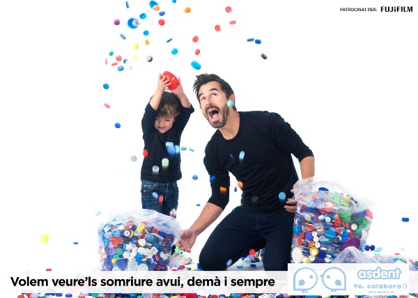 Peu de foto, logo de l'Associació de la malaltia de Dent (Asdent). Fotografia d’en Nacho i l’actor i presentador Santi Millan tirant taps de colors a l’aire.